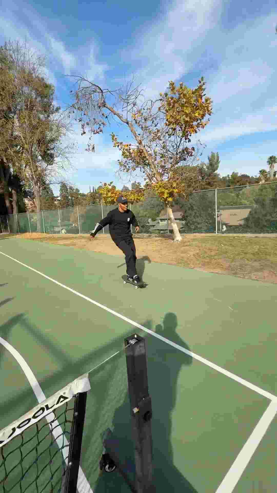 Felipe Gustavo skateboarding in a tennis court. Kickflips over a yellow bin and 180's over the court's net.